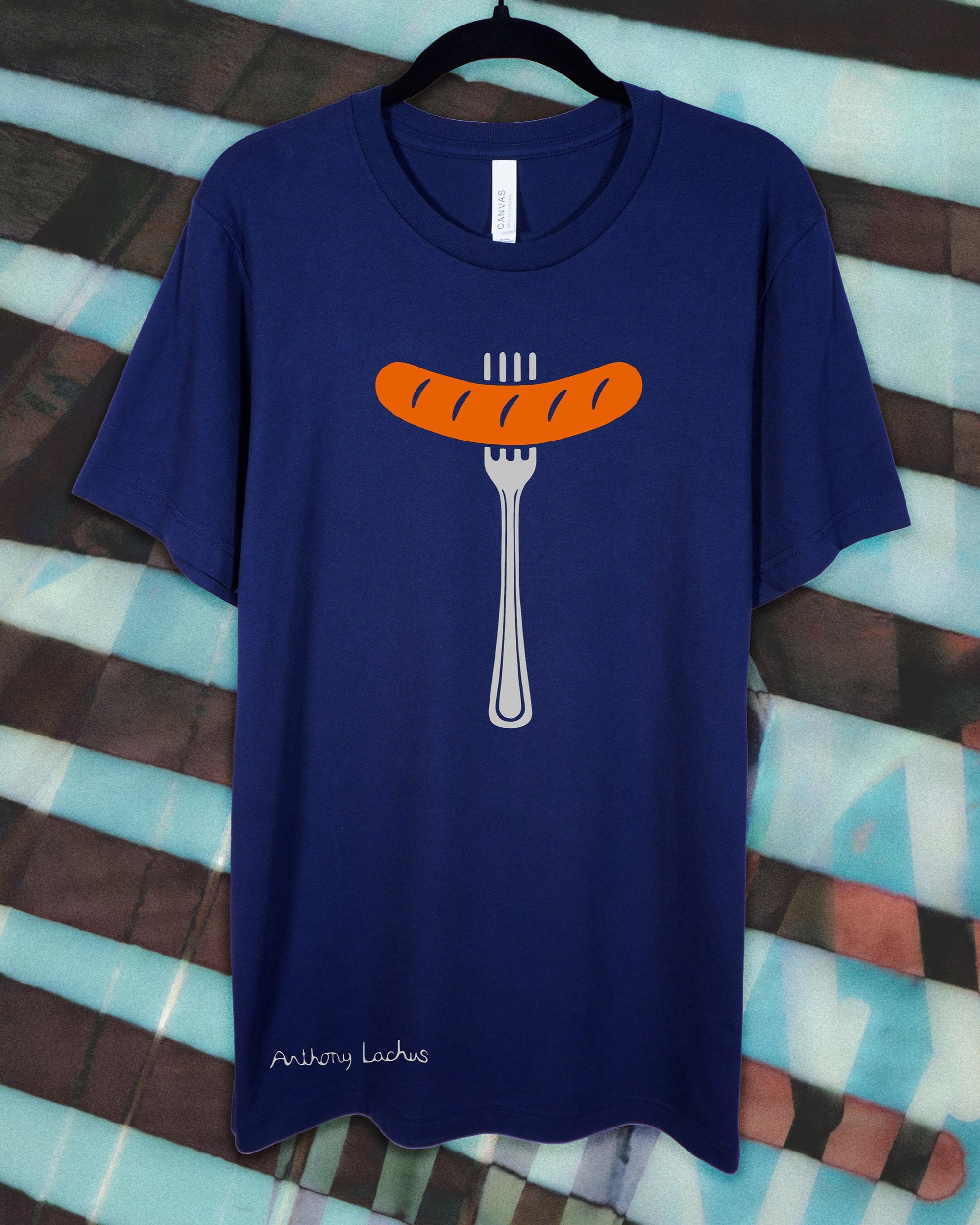 Blue t-shirt with a sausage and fork graphic on a colorful striped background