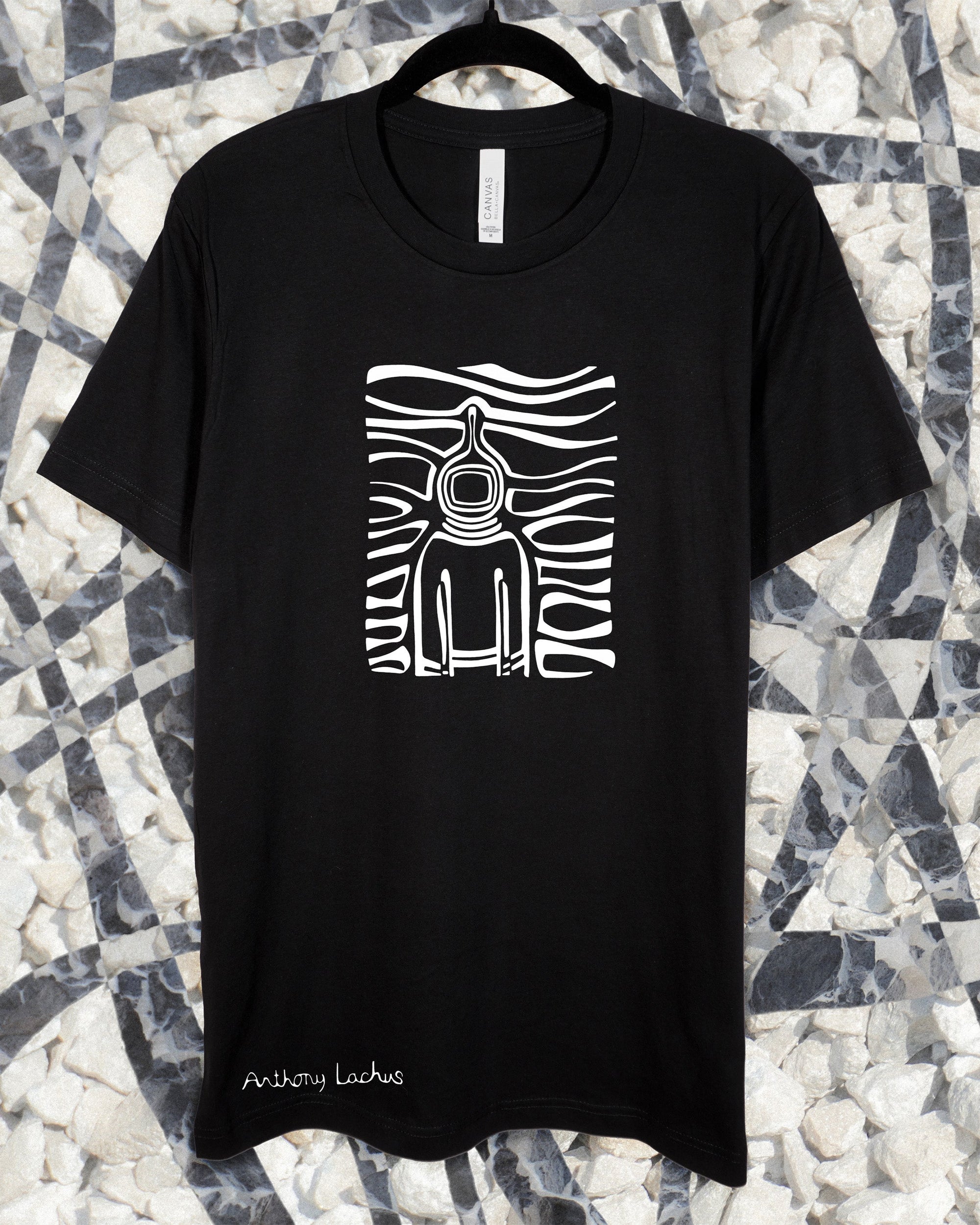 Black t-shirt with white graphic design of a space traveler on a patterned stone background