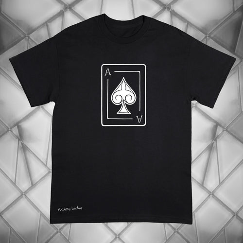 A black short-sleeve crewneck Gildan g500 t-shirt featuring a white graphic of an Ace of Spades playing card on the chest, with 'Anthony Lachus' printed in white script near the bottom left. The shirt is displayed flat against a gray geometric background.
