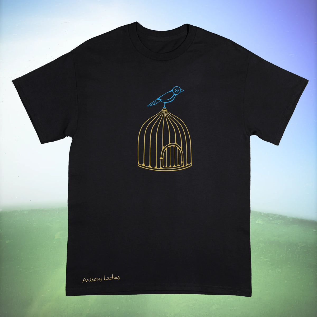 A black Gildan g500 crewneck t-shirt featuring a graphic design of a blue bird perched on a golden cage, laid flat against a green and white background. Original hand drawn artwork by Anthony Lachus. Front view.