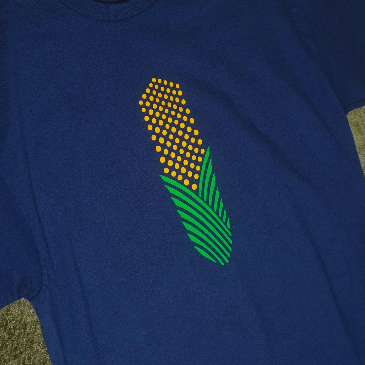 Green and yellow corn illustration on a navy blue Gildan g500 short sleeved t-shirt. Angle view. Original hand drawn artwork by Anthony Lachus.