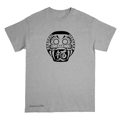 A heather gray short-sleeve t-shirt with a black Daruma doll graphic printed on the chest and a small 'Anthony Lachus' signature near the bottom left hem, shown against a plain white background.