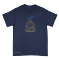 A navy blue short-sleeve crewneck t-shirt featuring a graphic of a blue bird perched on a gold wire birdcage. The name 'Anthony Lachus' is printed in a small gold script near the bottom left corner. An original, hand drawn artwork by Anthony Lachus.